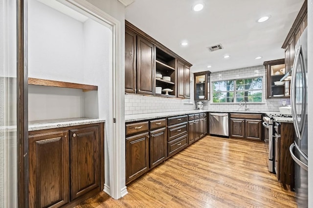 2802 Brandy Ln, Georgetown, TX 78628 - kitchen with dishwasher, open shelves, gas range oven, light wood-style flooring, and dark brown cabinetry