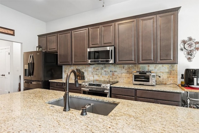 106 Chaumont St, Kingsland, TX 78639 - kitchen with appliances with stainless steel finishes, dark brown cabinets, tasteful backsplash, and light stone countertops