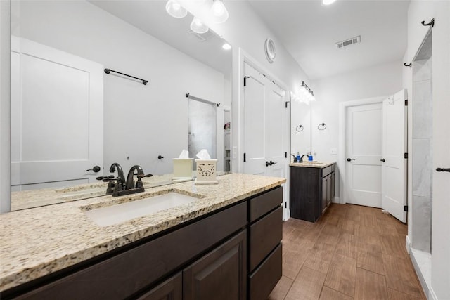 106 Chaumont St, Kingsland, TX 78639 - bathroom featuring a stall shower, two vanities, and wood finished floors