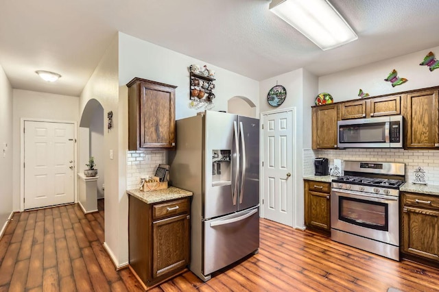 803 Ranchero Rd, Leander, TX 78641 - kitchen featuring stainless steel appliances, decorative backsplash, dark wood finished floors, and arched walkways