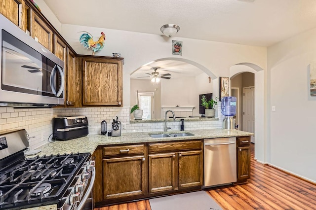 803 Ranchero Rd, Leander, TX 78641 - kitchen featuring stainless steel appliances, a ceiling fan, light wood-type flooring, and arched walkways