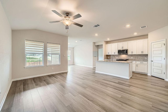 2871 Mill Run Bnd, Round Rock, TX 78665 - kitchen featuring stainless steel microwave, open floor plan, a ceiling fan, light wood-style floors, and white cabinetry