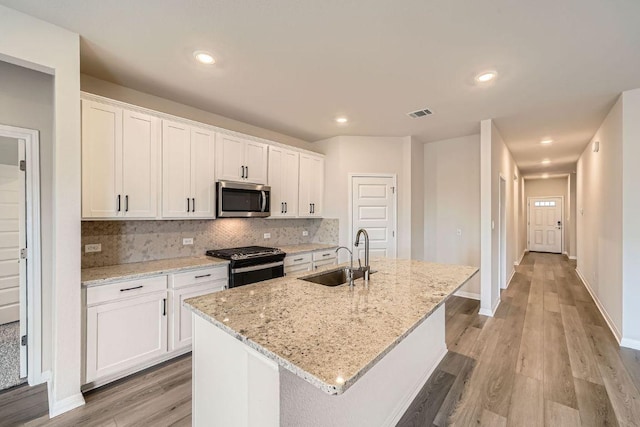 2871 Mill Run Bnd, Round Rock, TX 78665 - kitchen featuring stainless steel microwave, gas range, light wood-type flooring, white cabinets, and recessed lighting