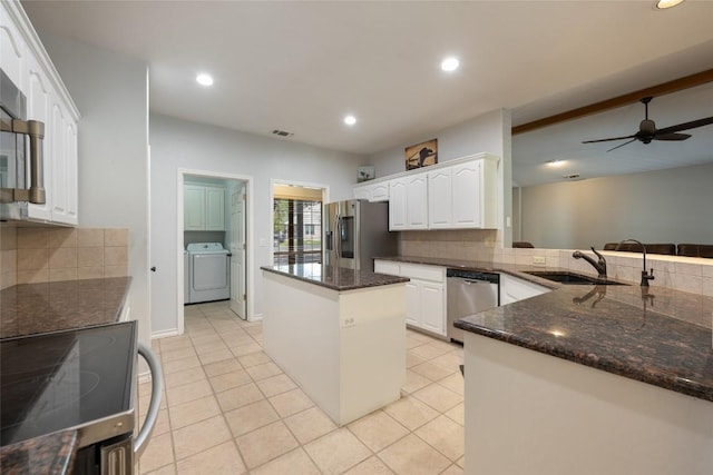 401 N Fox Xing, Burnet, TX 78611 - kitchen featuring appliances with stainless steel finishes, washer / dryer, tasteful backsplash, white cabinetry, and a kitchen island