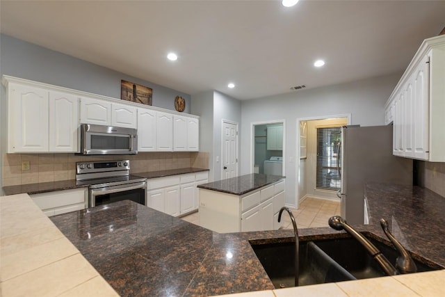 401 N Fox Xing, Burnet, TX 78611 - kitchen featuring appliances with stainless steel finishes, washer / dryer, tasteful backsplash, white cabinetry, and a center island