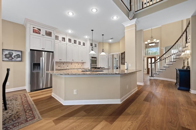 10008 Inshore Dr, Austin, TX 78730 - kitchen featuring stainless steel refrigerator with ice dispenser, wood finished floors, recessed lighting, light stone countertops, and a high ceiling