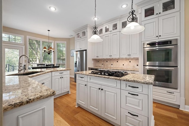 10008 Inshore Dr, Austin, TX 78730 - kitchen with appliances with stainless steel finishes, a center island, light wood-type flooring, decorative backsplash, and recessed lighting