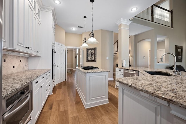 10008 Inshore Dr, Austin, TX 78730 - kitchen with gas cooktop, light wood finished floors, a kitchen island, decorative backsplash, and white cabinets