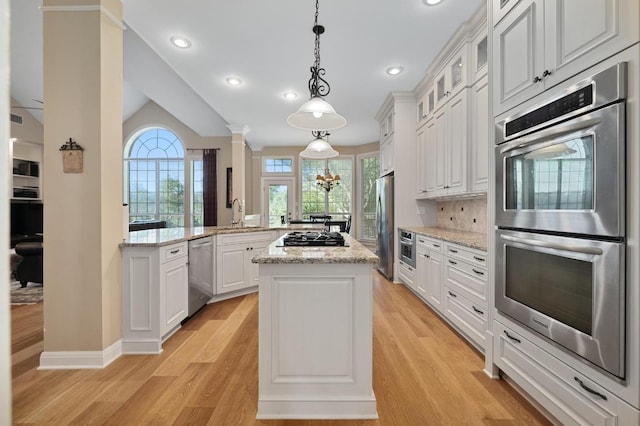 10008 Inshore Dr, Austin, TX 78730 - kitchen featuring stainless steel appliances, a kitchen island, light wood finished floors, glass insert cabinets, and white cabinets