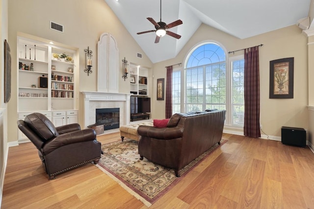 10008 Inshore Dr, Austin, TX 78730 - living room featuring light wood-type flooring, a ceiling fan, a premium fireplace, built in shelves, and high vaulted ceiling
