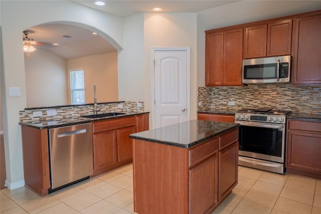11612 Yeadon Way, Austin, TX 78717 - kitchen with appliances with stainless steel finishes, a ceiling fan, decorative backsplash, dark stone counters, and arched walkways
