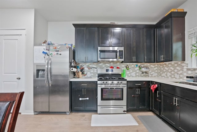 1519 Fenton Hill Dr, Leander, TX 78641 - kitchen with appliances with stainless steel finishes, light countertops, decorative backsplash, and light wood-style floors