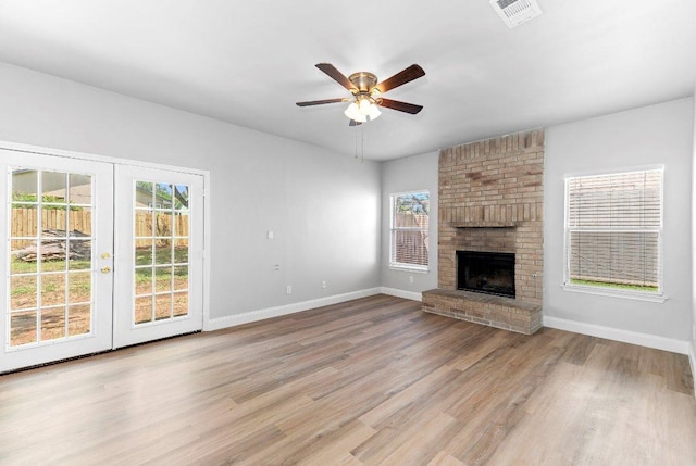 1207 York Castle Dr, Pflugerville, TX 78660 - unfurnished living room featuring wood finished floors, a ceiling fan, french doors, and a brick fireplace