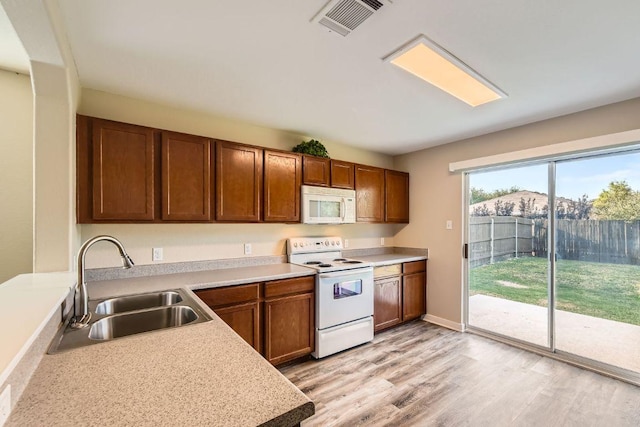 132 Hillhouse Ln, Manchaca, TX 78652 - kitchen featuring white appliances, light wood-style floors, light countertops, and brown cabinetry