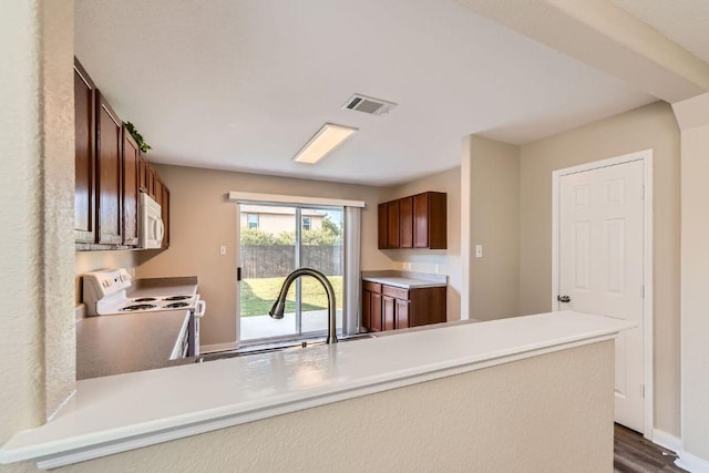 132 Hillhouse Ln, Manchaca, TX 78652 - kitchen with white appliances, a peninsula, and dark wood-type flooring