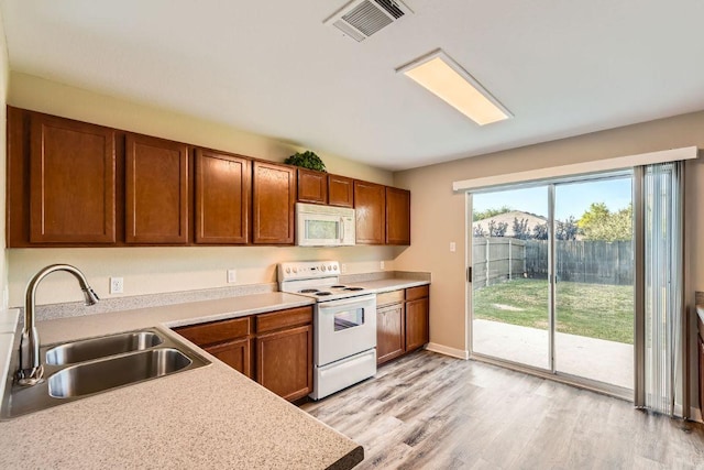 132 Hillhouse Ln, Manchaca, TX 78652 - kitchen featuring white appliances, light countertops, brown cabinets, and light wood-type flooring