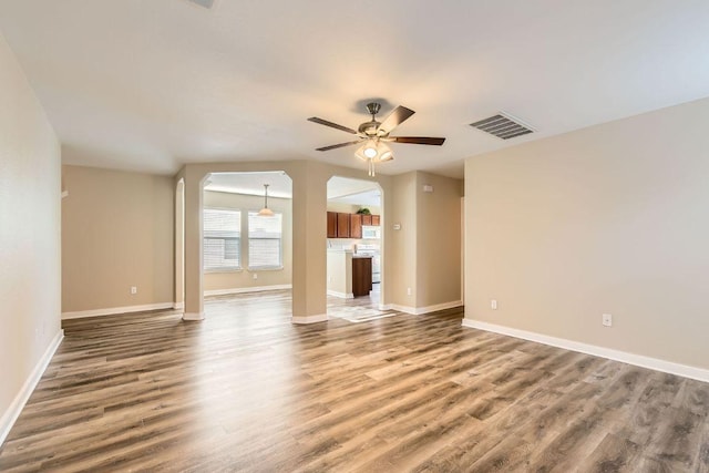 132 Hillhouse Ln, Manchaca, TX 78652 - unfurnished living room with a ceiling fan, wood finished floors, and arched walkways