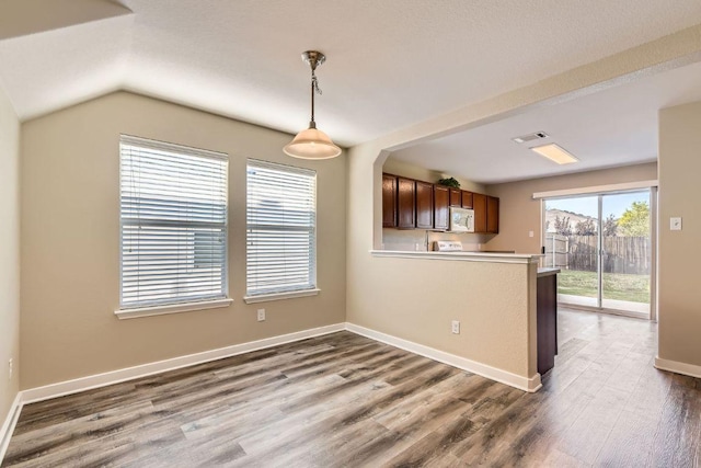 132 Hillhouse Ln, Manchaca, TX 78652 - kitchen featuring white microwave, a peninsula, light countertops, wood finished floors, and pendant lighting