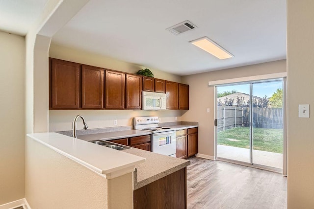 132 Hillhouse Ln, Manchaca, TX 78652 - kitchen featuring white appliances, light countertops, light wood-style floors, a peninsula, and brown cabinetry