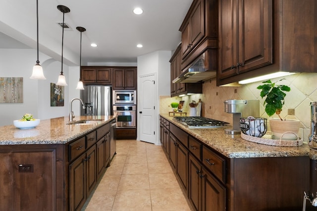 139 Merion Dr, Austin, TX 78737 - kitchen featuring stainless steel appliances, decorative backsplash, dark brown cabinetry, a kitchen island with sink, and decorative light fixtures