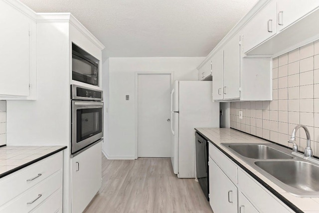 17226 Rocky Ridge Rd, Austin, TX 78734 - kitchen with black appliances, tasteful backsplash, white cabinets, light wood-style floors, and a textured ceiling