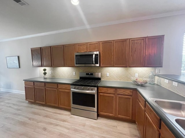 209 Crockett Loop, Georgetown, TX 78633 - kitchen with stainless steel appliances, brown cabinets, ornamental molding, backsplash, and dark countertops