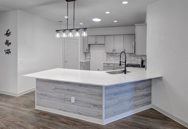 228 Tequilana Pass, Leander, TX 78641 - kitchen featuring gray cabinetry, a peninsula, recessed lighting, tasteful backsplash, and dark wood-style flooring