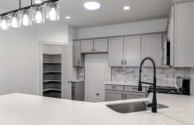 228 Tequilana Pass, Leander, TX 78641 - kitchen with gray cabinets, stainless steel microwave, black range with gas stovetop, backsplash, and recessed lighting