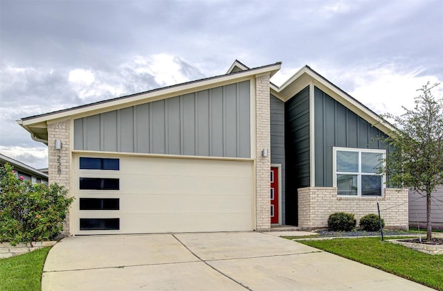 228 Tequilana Pass, Leander, TX 78641 - view of front of home with board and batten siding, a garage, concrete driveway, and brick siding
