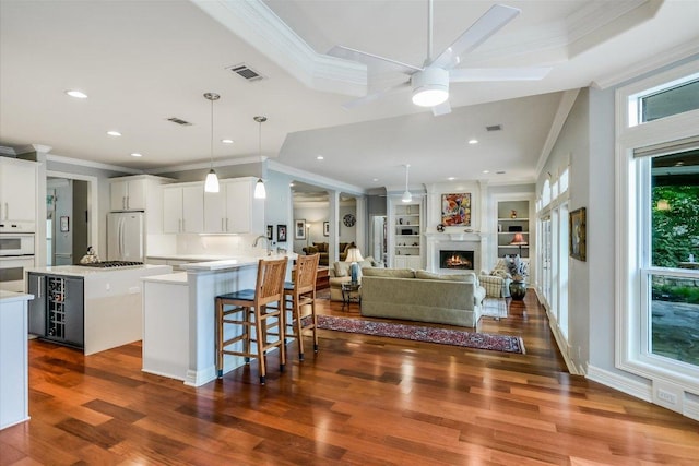 1208 Verdant Way, Austin, TX 78746 - kitchen with white appliances, beverage cooler, ornamental molding, a kitchen island, and dark wood-style floors