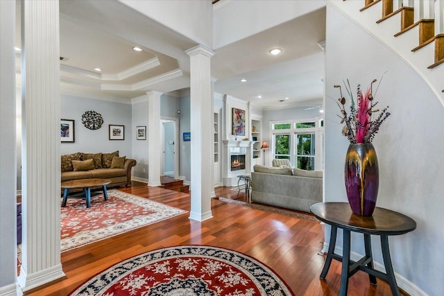 1208 Verdant Way, Austin, TX 78746 - foyer featuring ornate columns, crown molding, wood finished floors, a warm lit fireplace, and recessed lighting