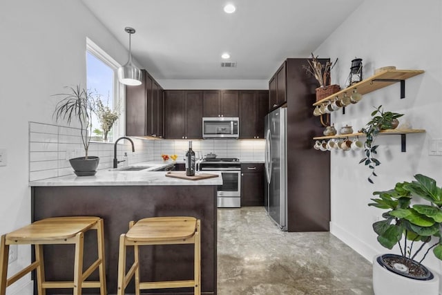 5006 Lott Ave Unit 2, Austin, TX 78721 - kitchen with appliances with stainless steel finishes, a peninsula, backsplash, dark brown cabinets, and hanging light fixtures