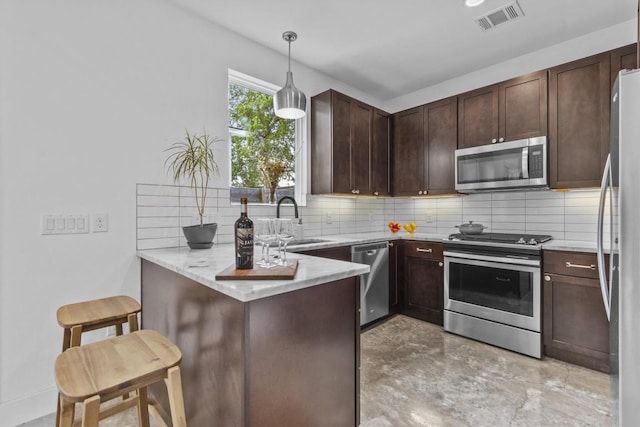 5006 Lott Ave Unit 2, Austin, TX 78721 - kitchen with appliances with stainless steel finishes, a peninsula, decorative backsplash, and dark brown cabinetry