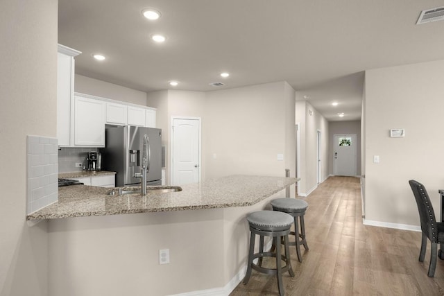 649 Otto Ave, Georgetown, TX 78626 - kitchen with stainless steel fridge, recessed lighting, light wood-type flooring, a peninsula, and light stone countertops