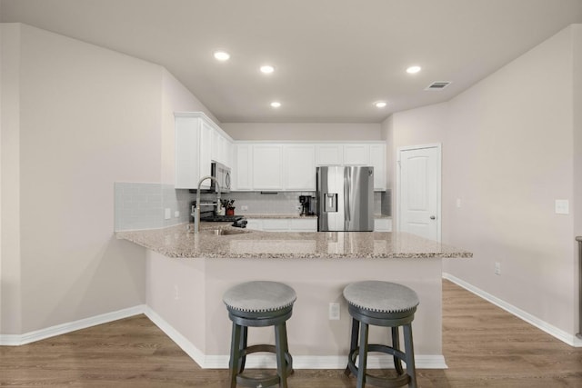 649 Otto Ave, Georgetown, TX 78626 - kitchen with appliances with stainless steel finishes, a peninsula, decorative backsplash, wood finished floors, and recessed lighting