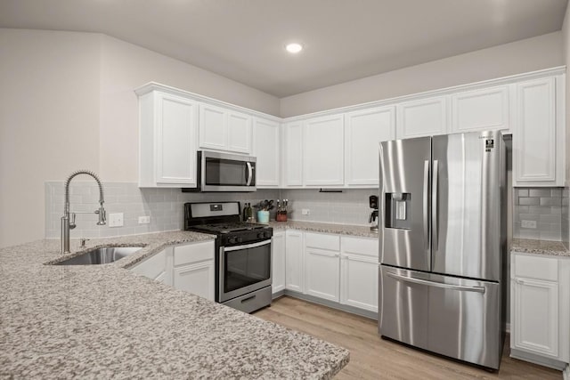 649 Otto Ave, Georgetown, TX 78626 - kitchen with appliances with stainless steel finishes, decorative backsplash, white cabinetry, light wood-style flooring, and light stone counters