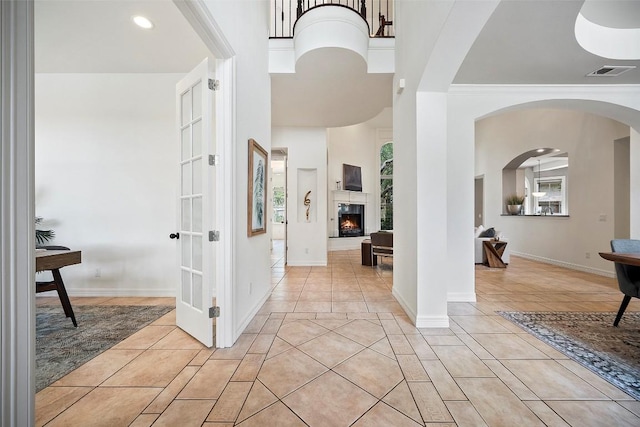10908 Sans Souci Pl, Austin, TX 78759 - foyer featuring light tile patterned floors, recessed lighting, arched walkways, a lit fireplace, and a towering ceiling