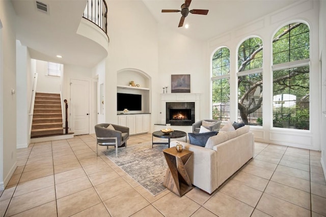 10908 Sans Souci Pl, Austin, TX 78759 - living area with built in shelves, a ceiling fan, stairway, light tile patterned flooring, and high vaulted ceiling