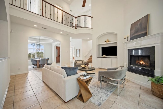 10908 Sans Souci Pl, Austin, TX 78759 - tiled living area with built in features, stairs, arched walkways, a warm lit fireplace, and a high ceiling