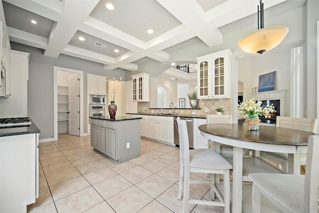 10908 Sans Souci Pl, Austin, TX 78759 - kitchen with appliances with stainless steel finishes, dark countertops, decorative backsplash, coffered ceiling, and glass insert cabinets