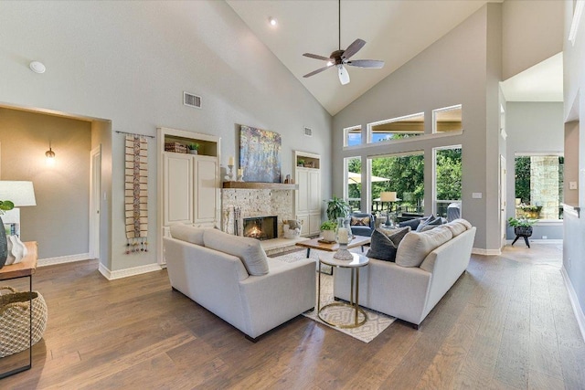 280 Whitney Run, Buda, TX 78610 - living area featuring high vaulted ceiling, wood finished floors, a ceiling fan, a stone fireplace, and healthy amount of natural light