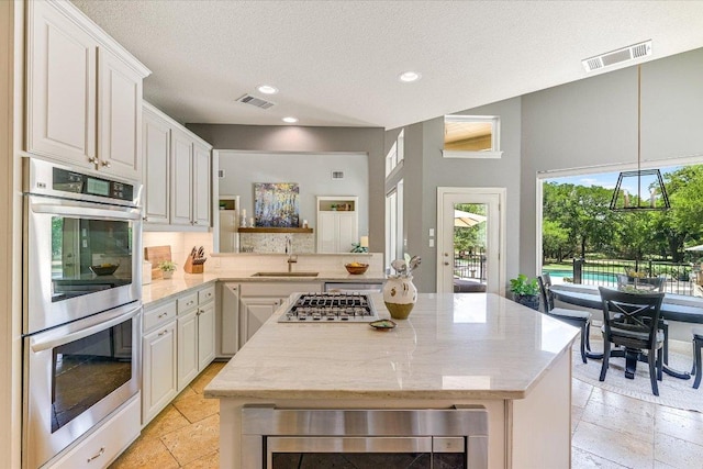 280 Whitney Run, Buda, TX 78610 - kitchen featuring appliances with stainless steel finishes, a kitchen island, recessed lighting, stone tile floors, and white cabinets