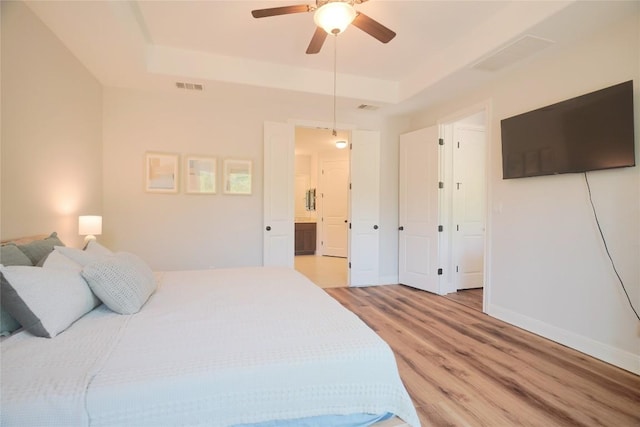 2301 Yaupon Range Dr, Leander, TX 78641 - bedroom with a tray ceiling, light wood-style flooring, and a ceiling fan