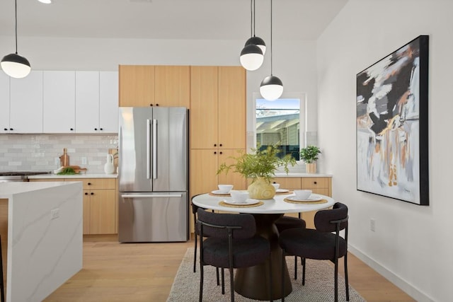3402 Goodwin Ave Unit 1, Austin, TX 78702 - kitchen with freestanding refrigerator, light wood-style floors, tasteful backsplash, and decorative light fixtures