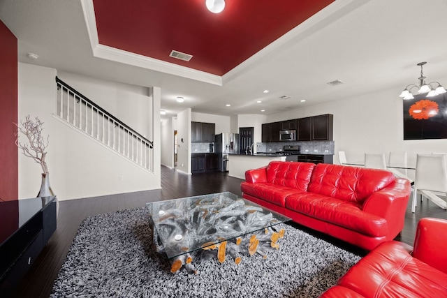 12000 Kincardine Way, Austin, TX 78754 - living room featuring a raised ceiling, dark wood-type flooring, a chandelier, stairs, and ornamental molding