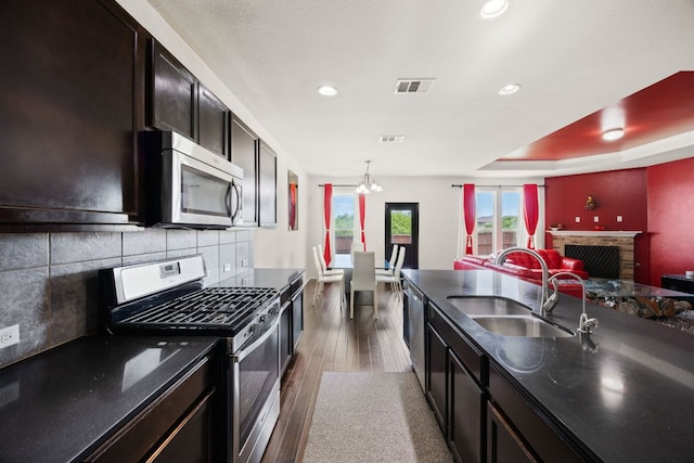 12000 Kincardine Way, Austin, TX 78754 - kitchen with stainless steel appliances, dark wood finished floors, a chandelier, a fireplace with raised hearth, and open floor plan