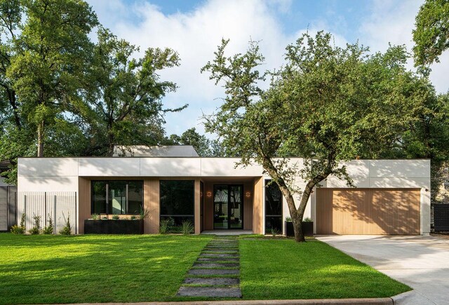contemporary home with concrete driveway, a front lawn, and an attached garage