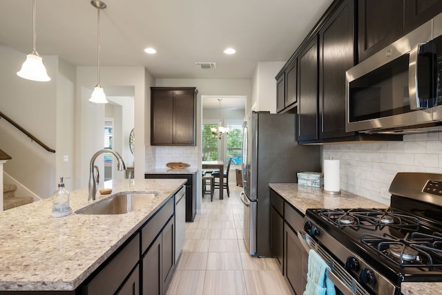 8713 Alderman Dr, Austin, TX 78747 - kitchen with appliances with stainless steel finishes, light stone counters, backsplash, an island with sink, and hanging light fixtures