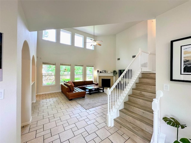 12504 Gun Metal Dr, Austin, TX 78739 - staircase with ceiling fan, a fireplace, a towering ceiling, and arched walkways