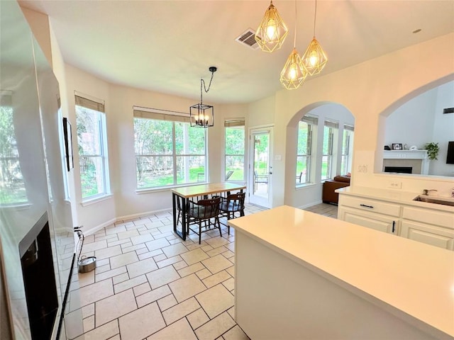 12504 Gun Metal Dr, Austin, TX 78739 - kitchen featuring arched walkways, white cabinetry, light countertops, a chandelier, and hanging light fixtures